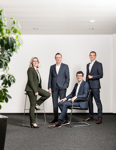 Business team photo of four standing in front of an office background photographed by photographer in Zurich