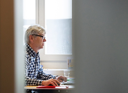 Person working at his desk with blurred foreground.
