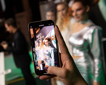 Photograph of a mobile display showing 3 models on the screen and blurred in the background.