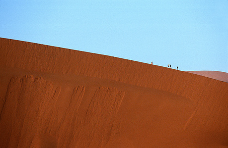 Namibia is the second-least densely populated country in the world – people walking on top of sand dune.