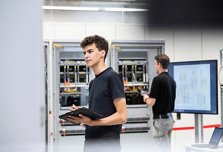 Engineers standing in front of panel in factory.