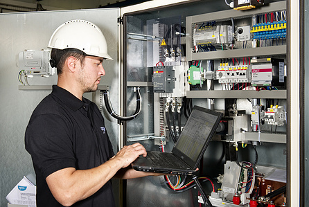 Engineer in front of panel with notebook.