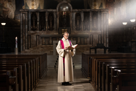 Editorial photography series showcasing people fom Zurich out of work due to Corona – Priest reading the bible in the church photographed by professional photographer in Zurich