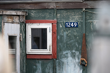 House wall with window and number late in small village in Greenland.