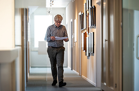 Person walking with documents in office hall.
