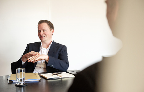 Reportage photography – person talking with blurred person in the foreground.