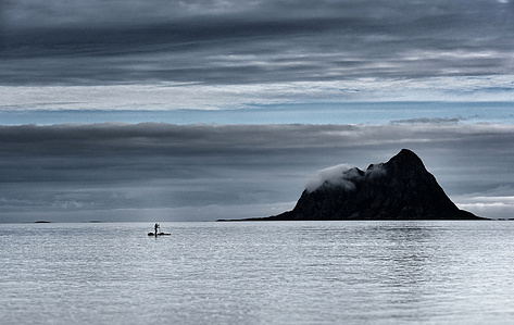 Stand up paddler in front of dark island in Norway.