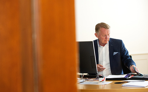 Editorial style photograph of employee sitting at his desk in an office in Zurich, Switzerland.