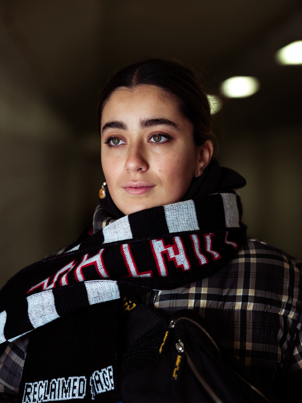 Colour photograph of a young Moroccan woman with a scarf wrapped around her neck looking out of the frame.