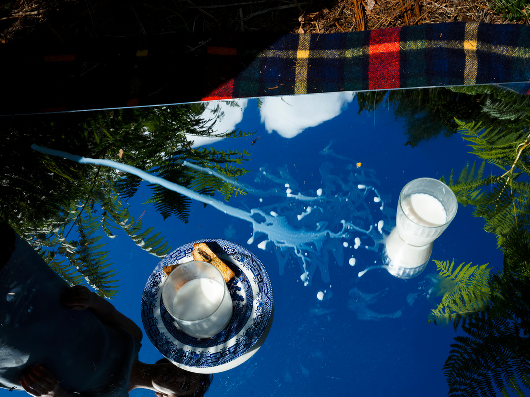 Close-up photograph of a picnic with some milk spilt across a mirror.