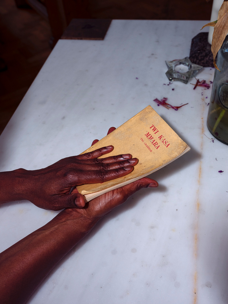 Colour photograph of the hands of a black person holding a Twi language dictionary.
