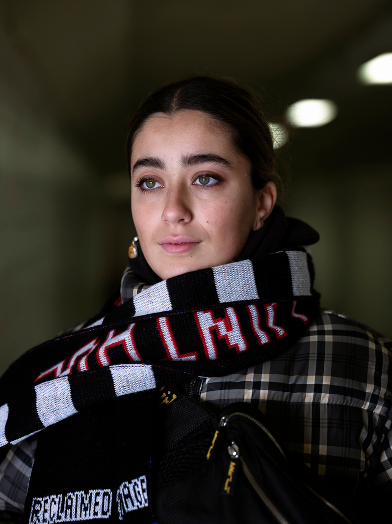 Colour photograph of a young Moroccan woman with a scarf wrapped around her neck looking out of the frame.