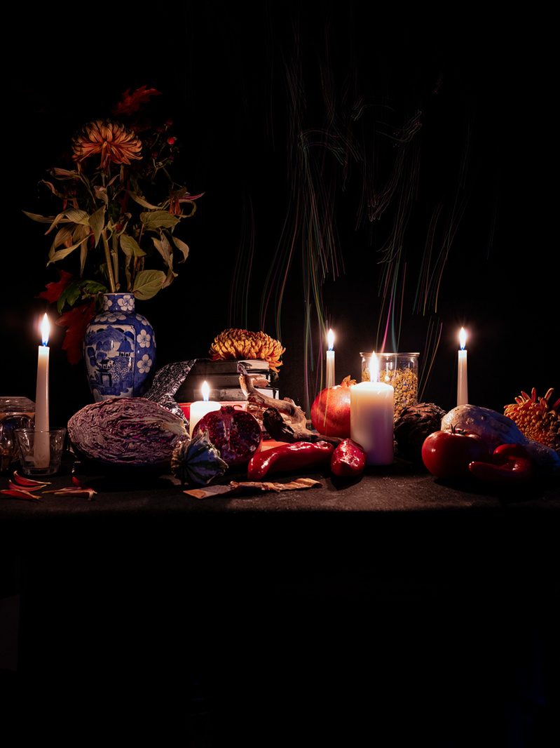 Colour photograph of a collection of personal items on a tabletop lit by candles.