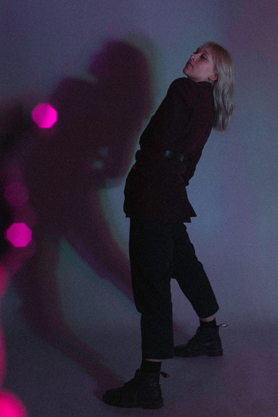 Editorial fashion model striking a pose in a studio in moody lighting.