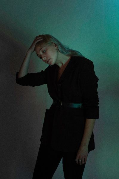 Editorial fashion model striking a pose in a studio in moody lighting.