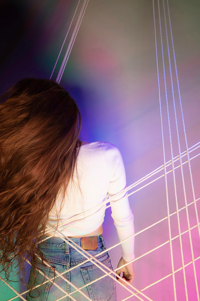 Lifestyle model with back to camera tossing hair back and forth against colorful backdrop.