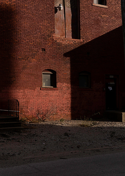 Fine art view of a red brick building in harsh sunlight with high contrast shadows.