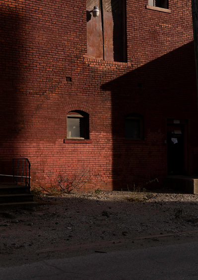 Fine art view of a red brick building in harsh sunlight with high contrast shadows.