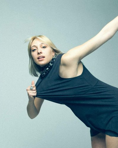 Editorial fashion model in a navy tank dress pulling herself forward by the dress and posing.