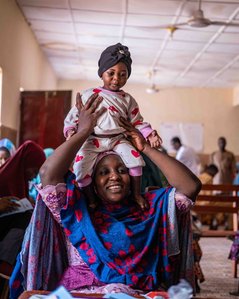SOKOTO, NGA - July 5, 2023: Rashida Umar smiles as carries Nana Firdausi at Rumbukawa Primary Health Care center, Sokoto state, Nigeria. CREDIT: Taiwo Aina 

