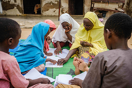 YOLA, NGA - October 4, 2023: Faiza Habibu studying with her children in front of her house in Dasin Hausa community, Fufoire LGA, Adamawa State Nigeria. CREDIT: Taiwo Aina for IRC