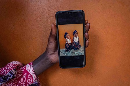 SOKOTO, NGA - July 4, 2023: Maryam Musa holds a phone showing portrait of AsmaÕu Kasimu and her twin in their home at Kofar Marke, Sokoto North LGA, Nigeria. CREDIT: Taiwo Aina 