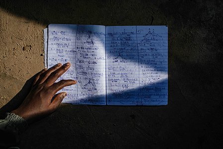 KADUNA, NGA - August 12, 2023:  Asiya Sa’idu,17, holding her book in front of her house at Dogon Bauchi, Sabon Gari, Kaduna State, Nigeria. Asiya aims to be a doctor or a teacher, “My future ambition is to become a medical doctor because we don’t have eno
