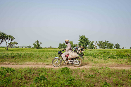 YOLA, NGA - October 3, 2023: Shaibu Mohammed heads back home with his motorcycle from his farm located in Dasin Hausa community, Fufoire LGA, Adamawa State Nigeria. Shaibu Mohammed is a beneficiary of Google climate resilency project. After receiving cash