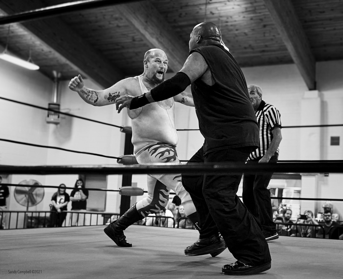 The wrestler approaches with aggression and a dramatic punch.