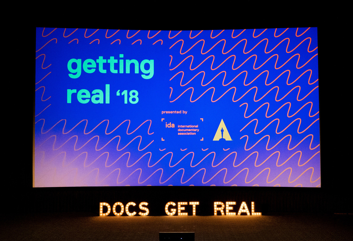 Getting Real '18 Documentary Conference with neon lights below the theater screen: DOCS GET REAL