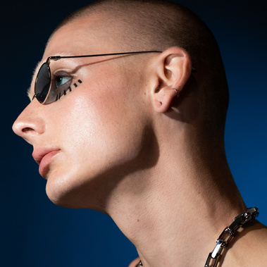 A non-binary model on a blue background in grunge 90s styling