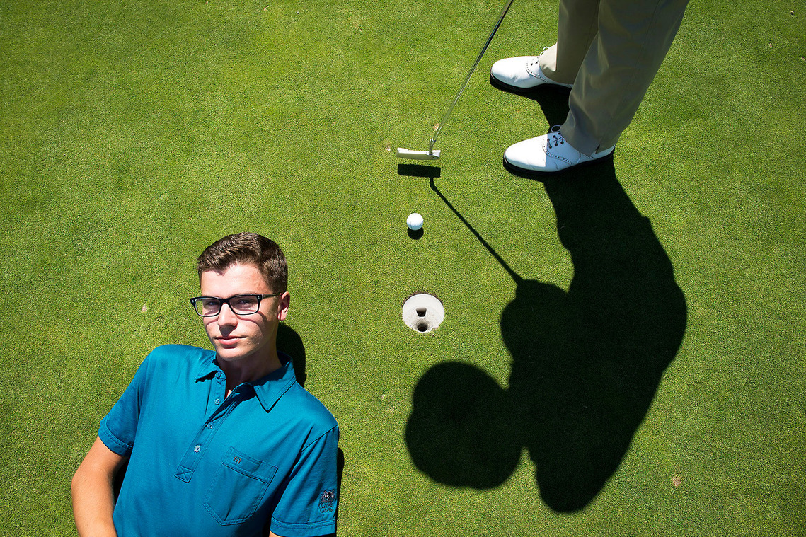 Lakewood golf player Brooks Venuti, 18, left, lies on the green as his teammate Justin Collins, 16, putts at the Lakewood Golf Course on Friday, April 2, 2014. 