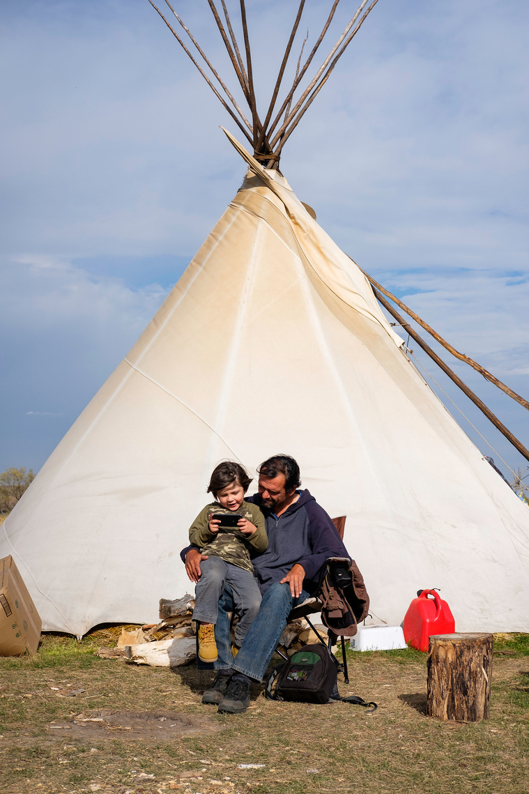 Unpa Nunpa, 48 of the Cheyenne River nation in South Dakota, sits with his grandson Kinya Luta, 5, at his campsite Saturday, Aug. 15 at Oceti Sakowin.