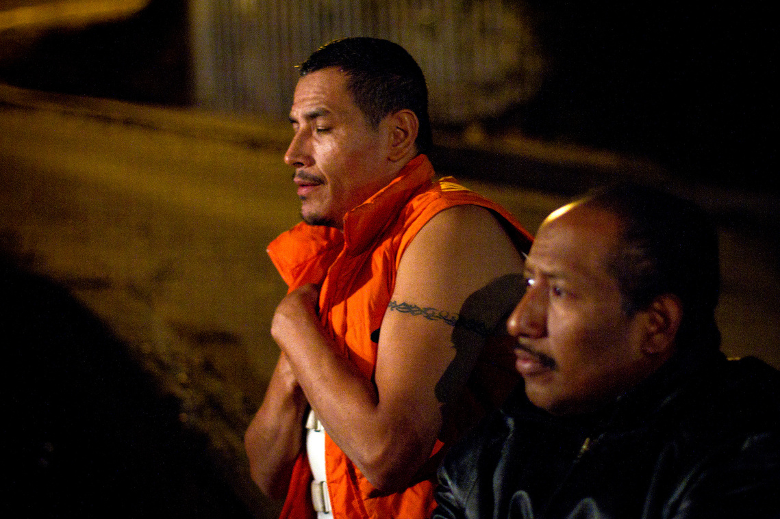 Rodriguez prays next to a volunteer at Albergue San Juan Bosco during a Saturday night mass. 