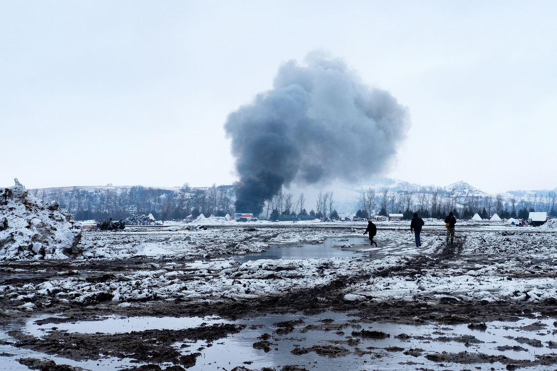 A structure burns in the distance as Dakota Access Pipeline protesters work to clear the Oceti Sakowin campground on Feb. 22, the day the Army Corps of Engineers ordered campers to clear the area.