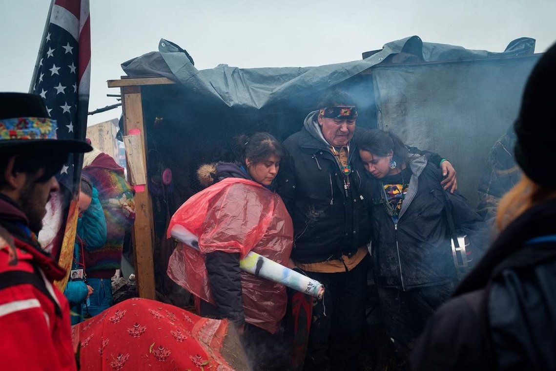 Raymond Kingfisher hugs loved ones as he gives a heartfelt speech thanking campers for their support and prayers at the Oceti Sakowin campground. 