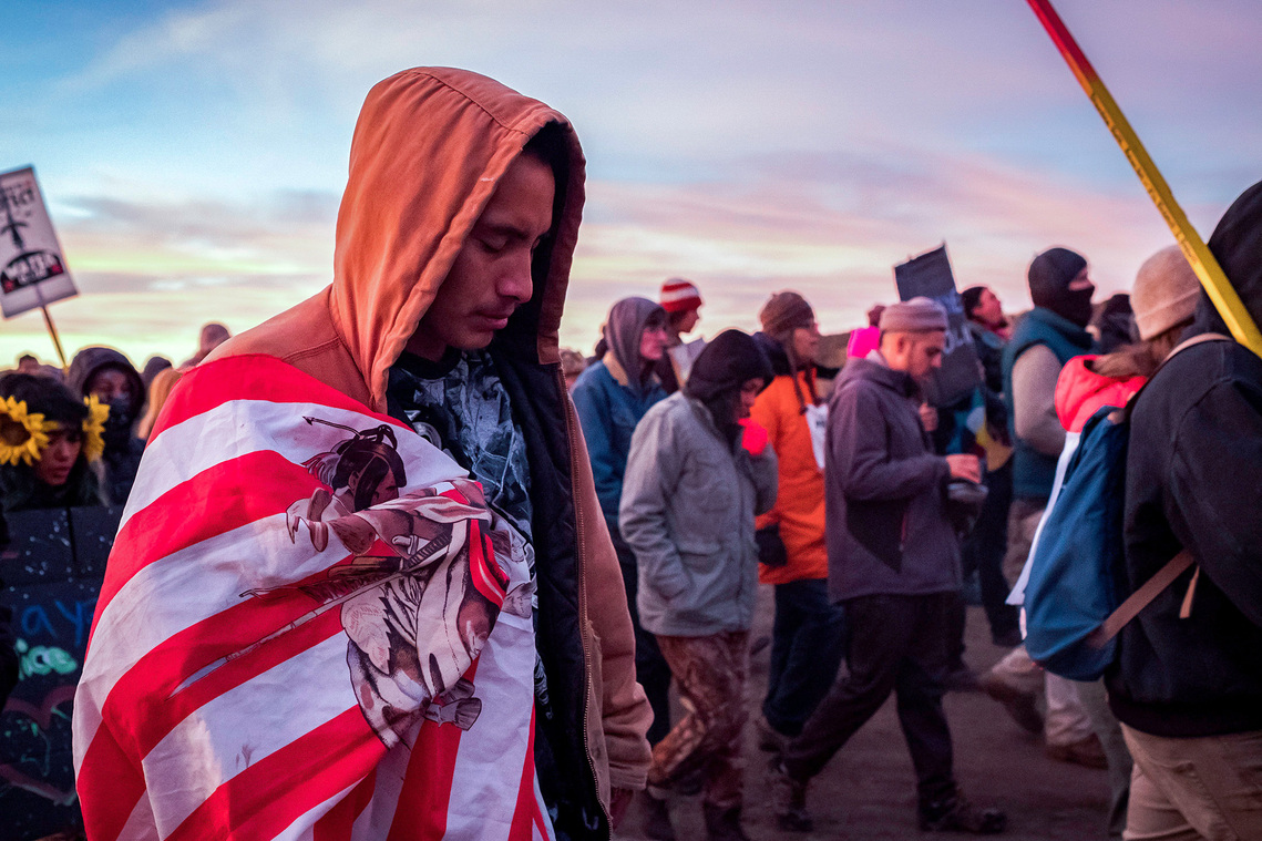 Mason Neck of Rosebud drapes a flag over his shoulder as he and more than 200 others march toward a Dakota Access pipeline construction site Saturday, Oct. 22 northwest of Cannon Ball, N.D.