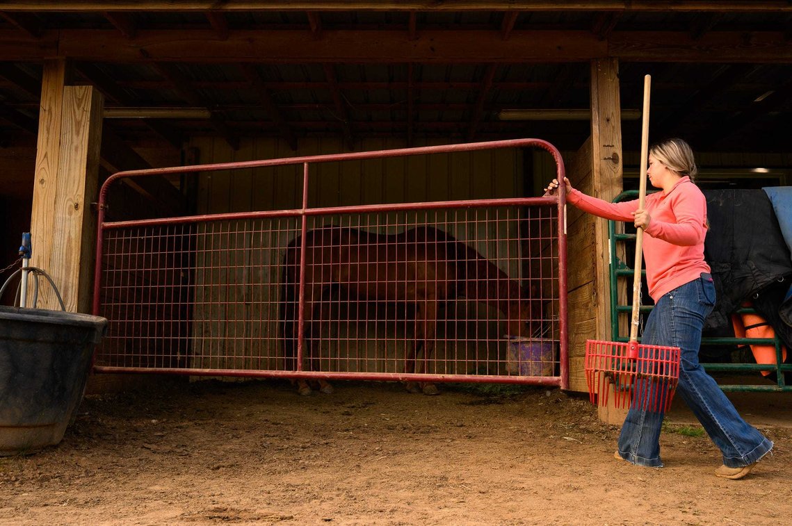 Sally Poteat opens the gate to clean the pens after feeding her five horses before going to school Tuesday, May 18, 2021.