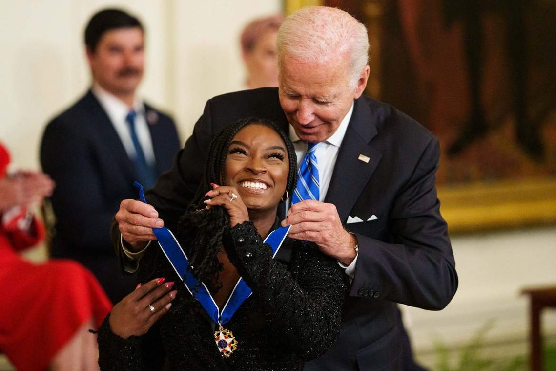 Gymnast Simone Biles smiles as President Joe Biden places a Medal of Freedom on her during the Presidential Medal of Freedom Ceremony at The White House Thursday, July 7, 2022.
