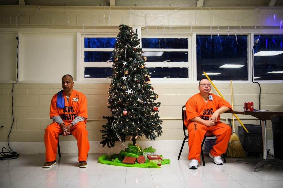 Two inmates sit down as they watch other inmates take part in a Christmas dinner event at Perry Correctional Institution Monday, Dec. 10, 2018.