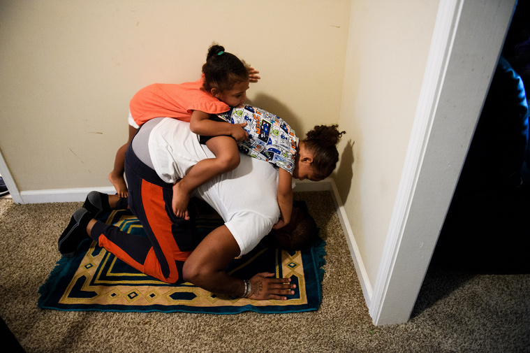 Yahya Grant and her brother Aliyah catch a ride their father Johnnie's back as he prays on Saturday, June 30, 2018.
