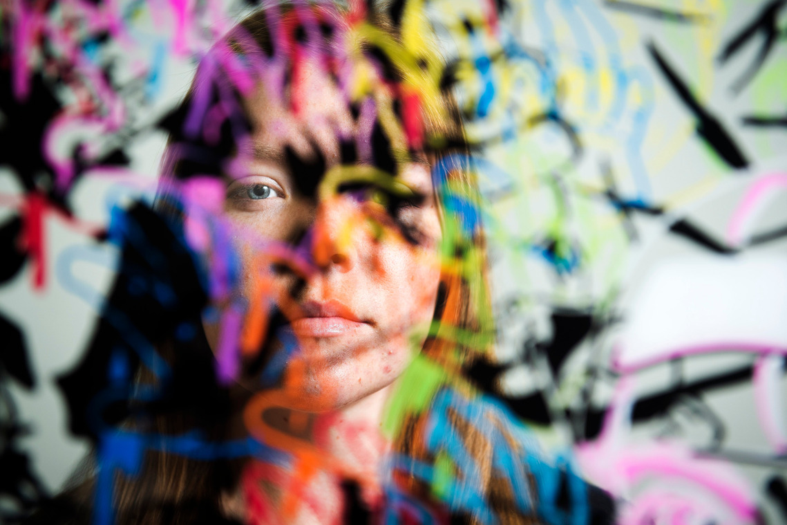 Millikan High School artist Alison Pirie stands behind one of one of her acrylic and ink pen pieces, 