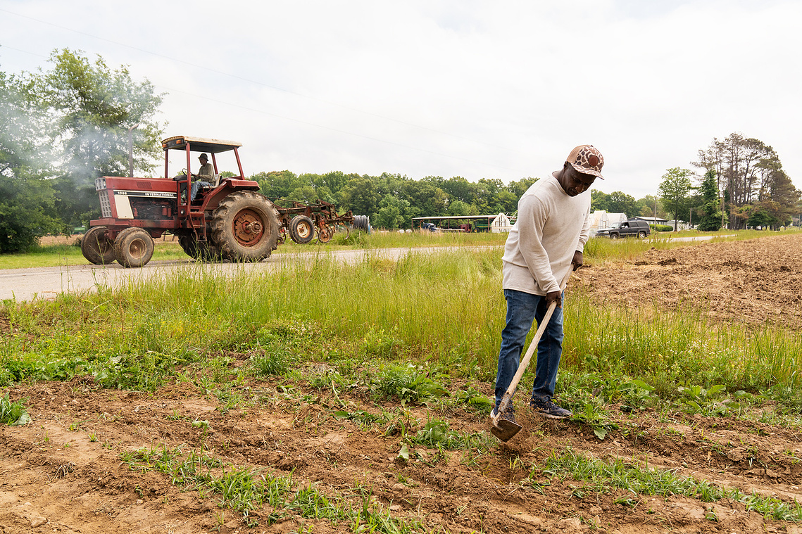 Calvin Head of the Mileston Farming Cooperative tills one of the co-op’s fields as LC Mitchell drives by on his tractor. 