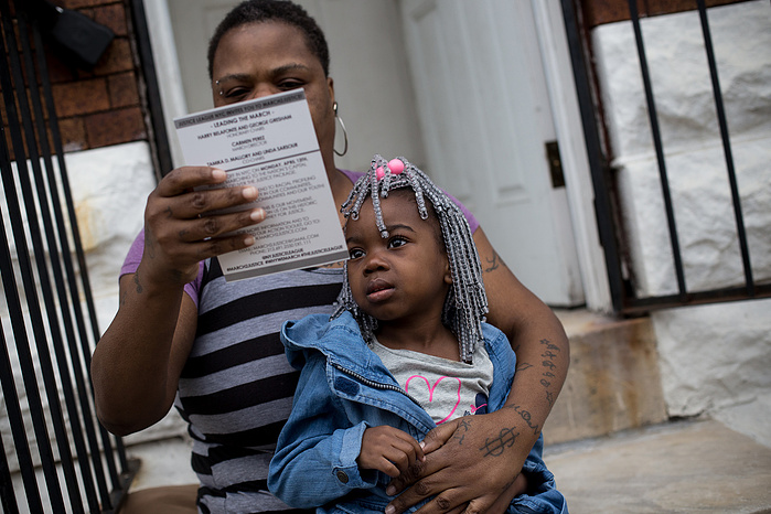 Baltimore residents inspect flyers handed out by marchers walking through west Baltimore.
