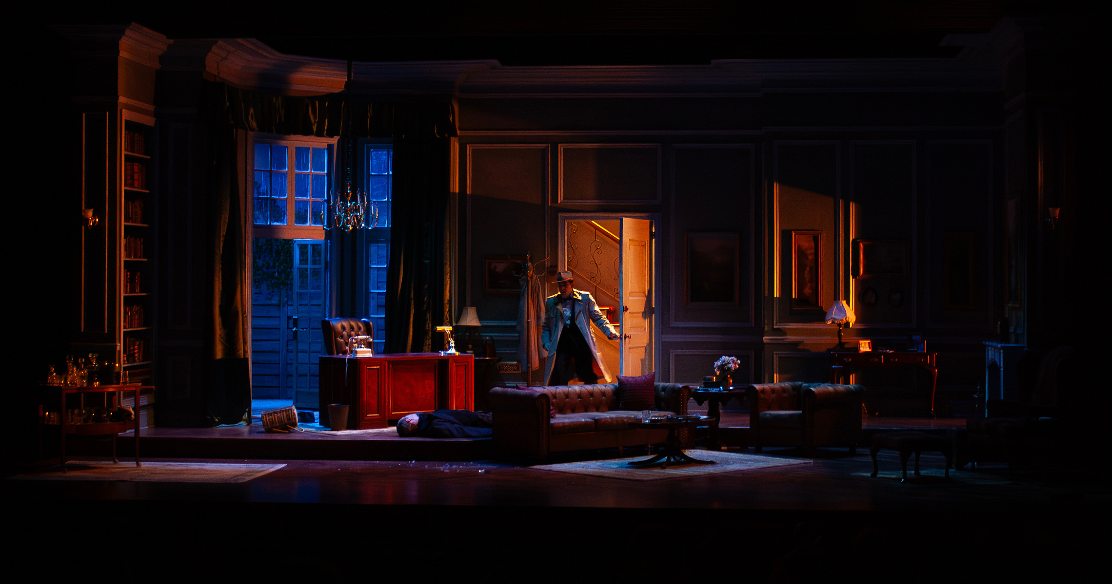 Paige Hathaway&#x27;s set design for &quot;Dial M for Murder&quot;, directed by Adam Immerwahr, at Village Theatre. The set is a tastefully decorated grand London flat with a parquet floor, panel moulding on the walls, and large bay windows looking out onto a garden.