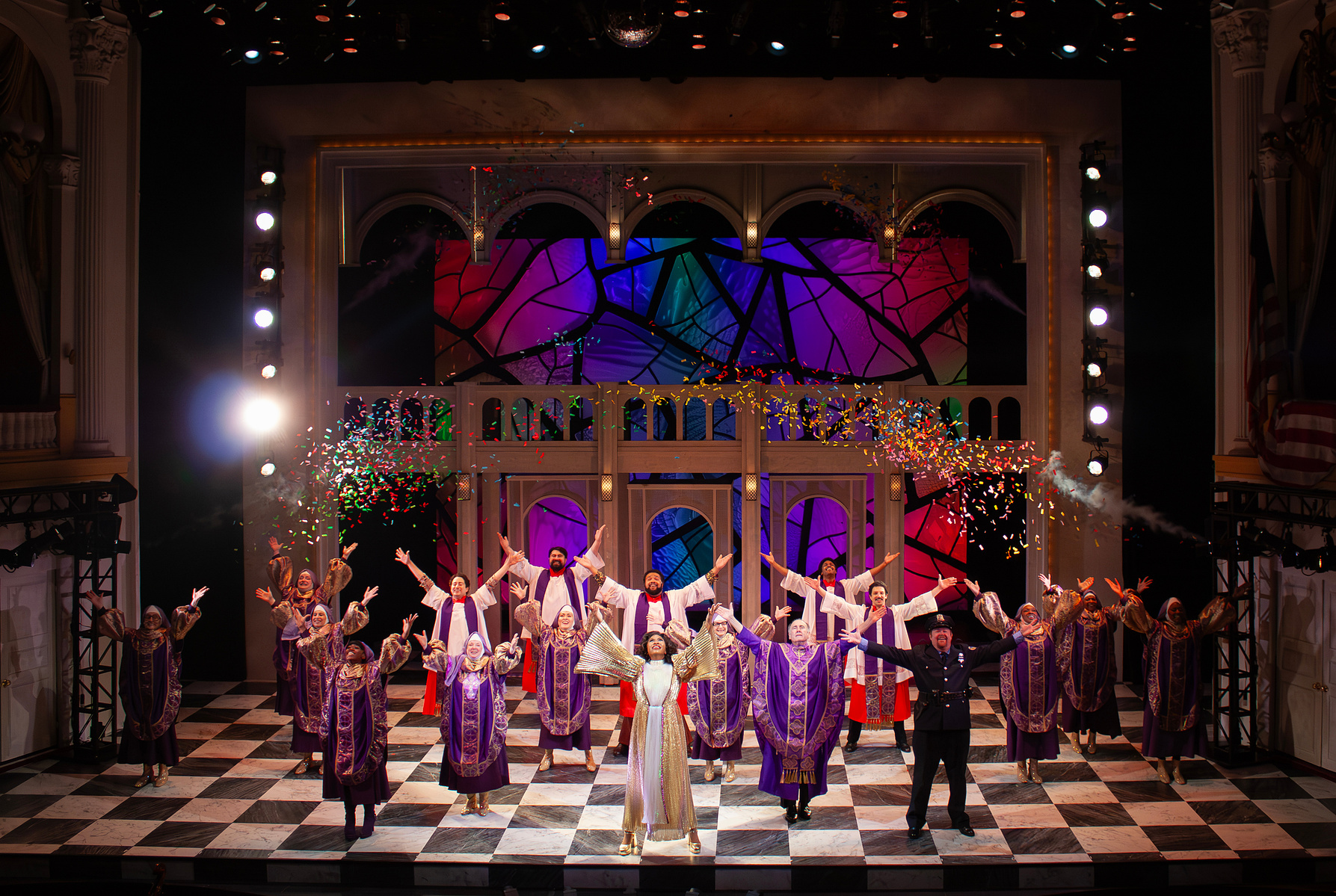 Paige Hathaway's scenic design for "Sister Act", directed by Jeff Calhoun at Ford's Theatre in 2025. The design consists of spinning panels, a large portal with theatrical lights, a checkerboard marble floor, and a backlit stained glass backdrop.