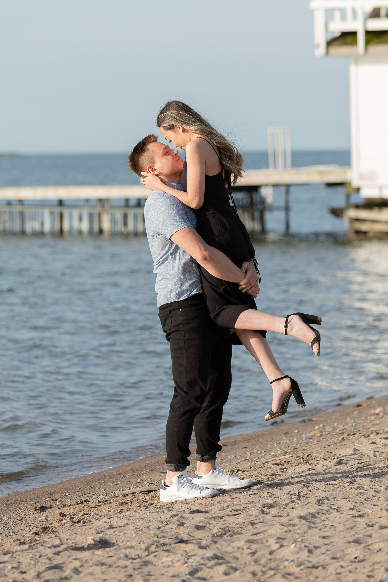 Couple at Cherry Beach in Toronto, ON. Man lifting woman up.