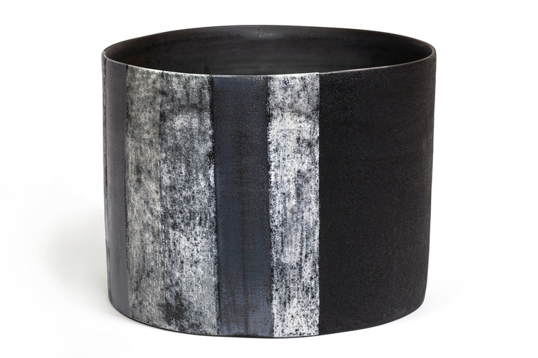 Artist Kathy Erteman created Grey Stripe Vessel, a wheel thrown ellipse sculptural ceramic vessel featuring texture stripes in a variety of greys over a black glaze, inspired by minimalist works of art.