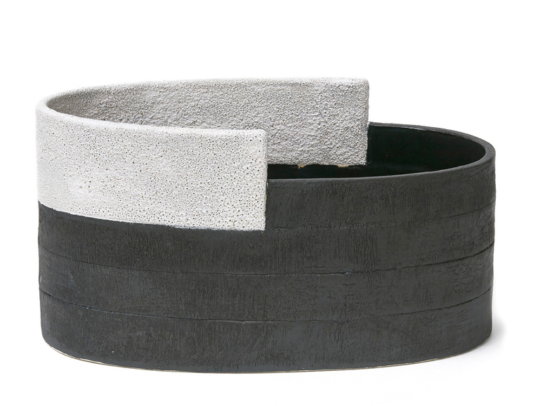 This hand-built stoneware oval vessel is titled White Ledge Vessel. Created by artist Kathy Erteman, the contemporary ceramic sculpture has an irregular inset top with a white frothy texture glaze, and black texture slip