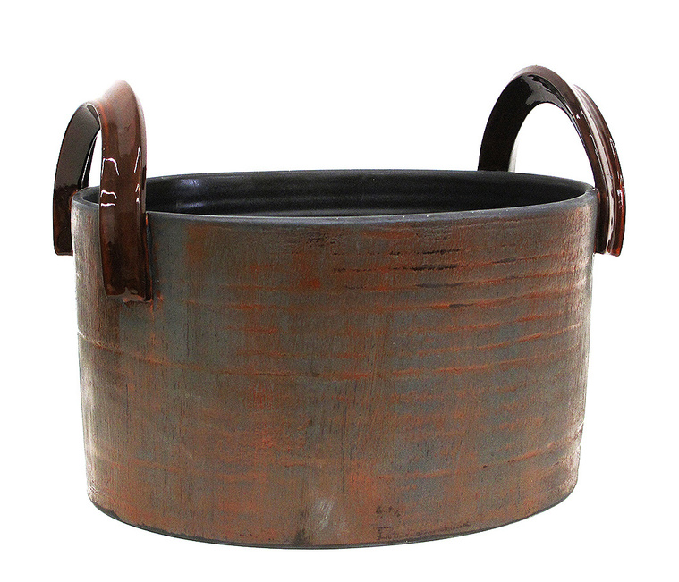 Titled Grey - Orange Oval Handles Vessel, this stoneware sculpture with loop handles was inspired by a basket. Wheel thrown and altered by Kathy Erteman, the ellipse form is minimal and the grey texture glaze with orange highlights luminous